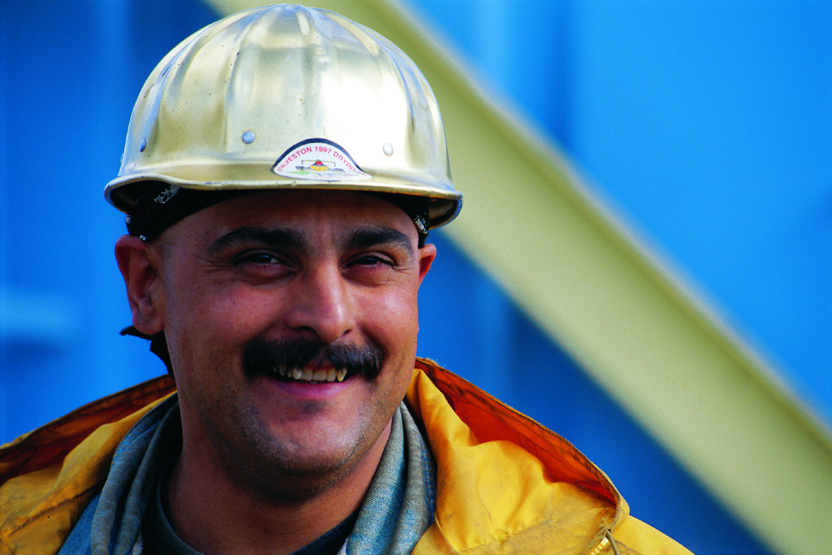 Construction worker with a mustache wearing a hard hat.