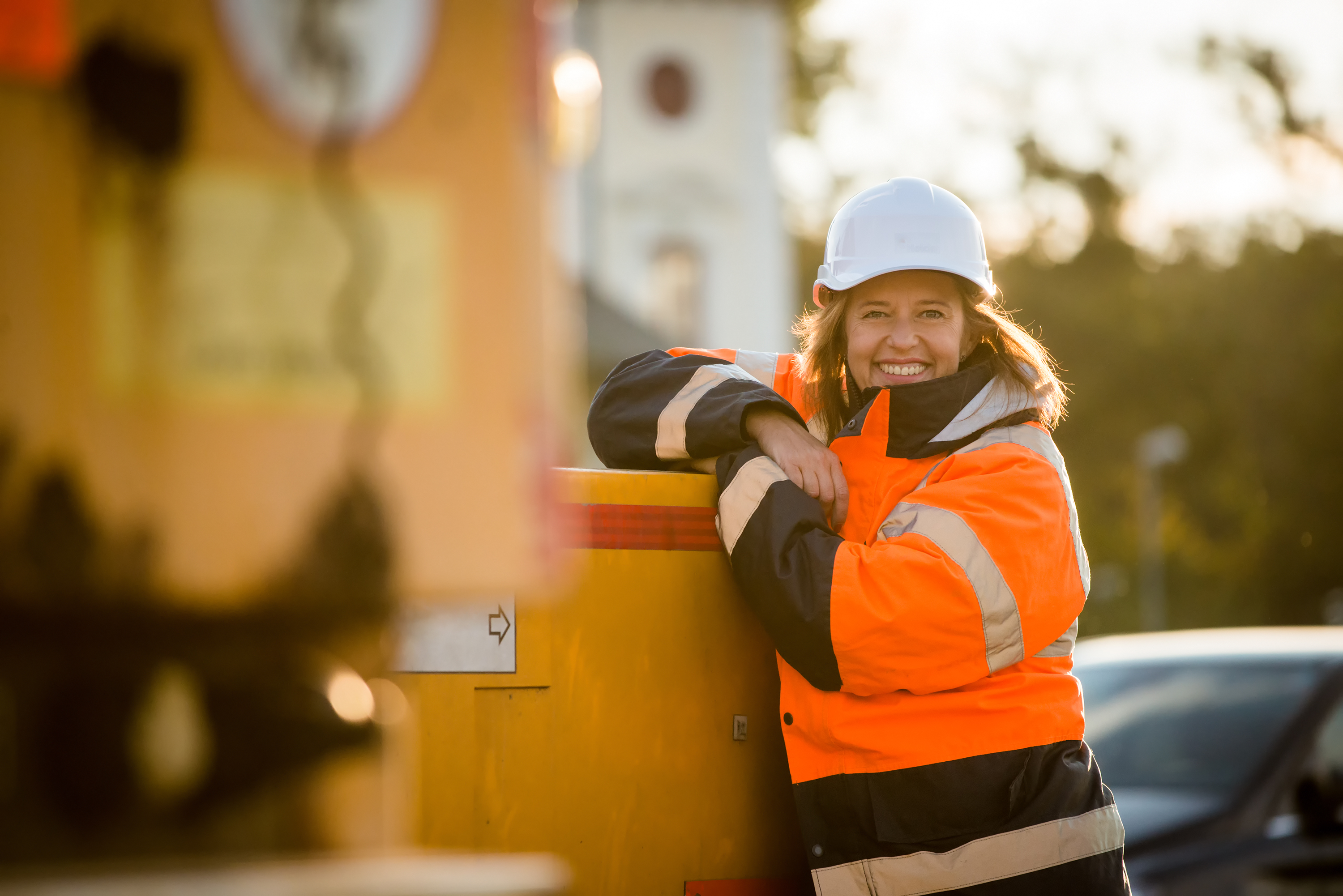 Woman builder at a construction site, wearing a hard hat and high visibility jacket.