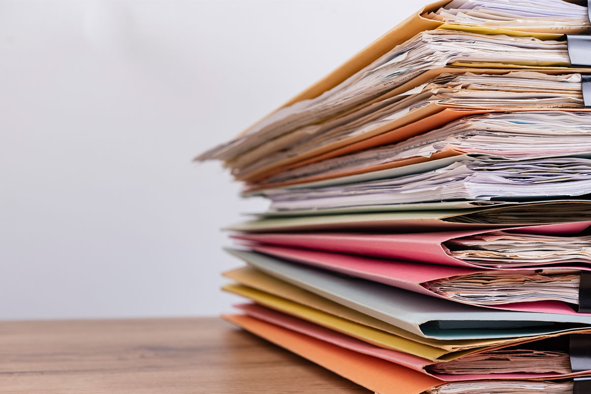 A stack of paper files on a desk.