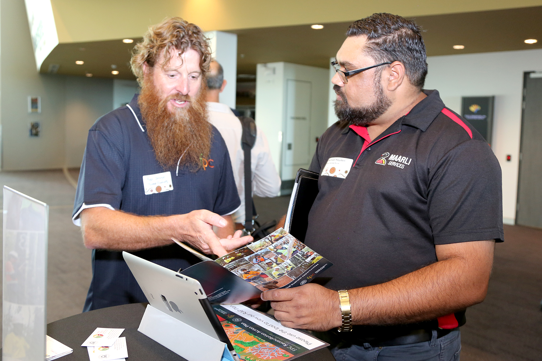 Two people discuss a brochure at an expo.