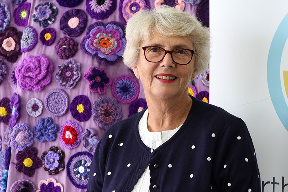 Judy Joukador standing in front of the Purple Road artwork.