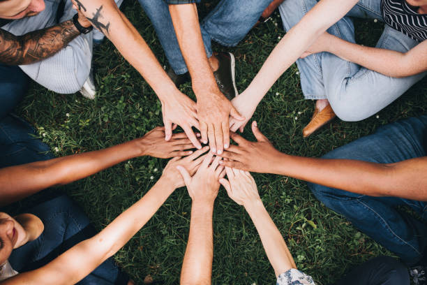 Community of people with their hands together in the centre of a circle