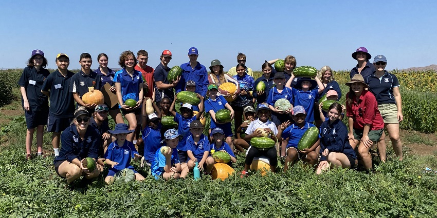 Students in crop holding watermelons and pumpkins