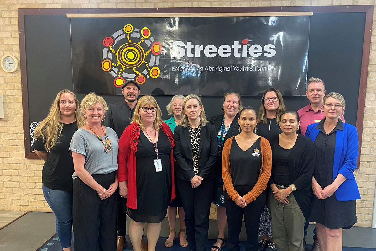 Image of Minister McGurk and stakeholders from Streetwork Aboriginal Corporation and Wungening Aboriginal Corporation. Streeties artwork in the background.