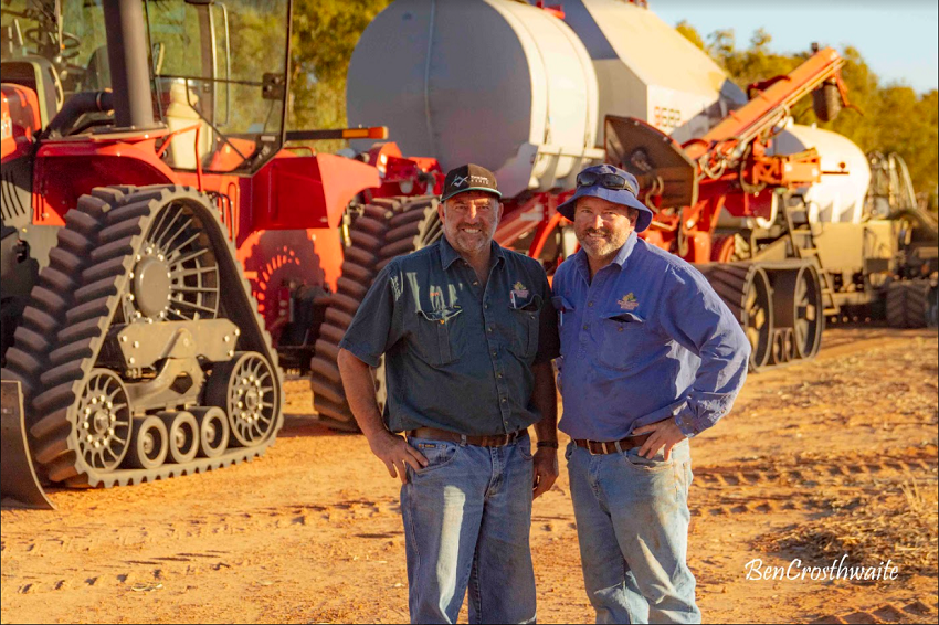 Two men standing in front of crop sowing machinery