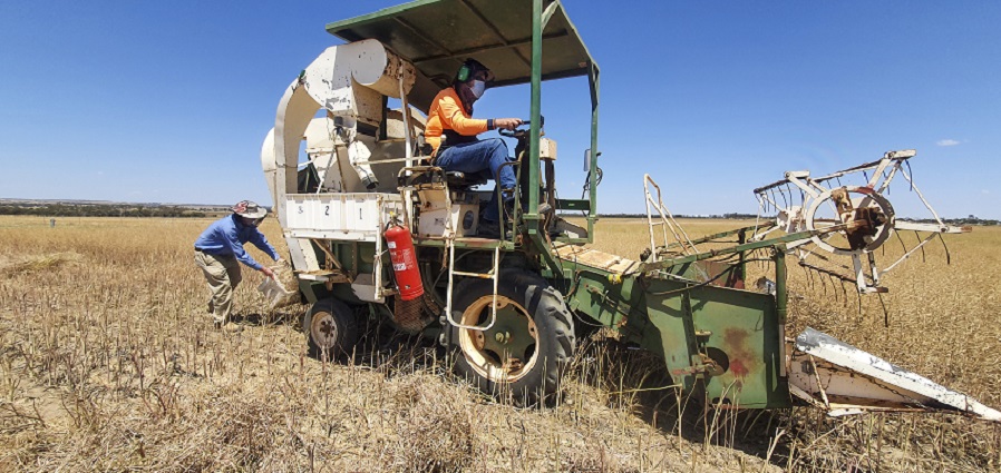 Man sitting on farming equipment with person walking behind