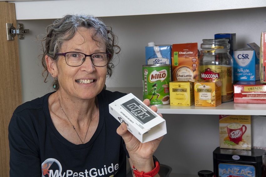 Woman standing in front of pantry holding a pest trap