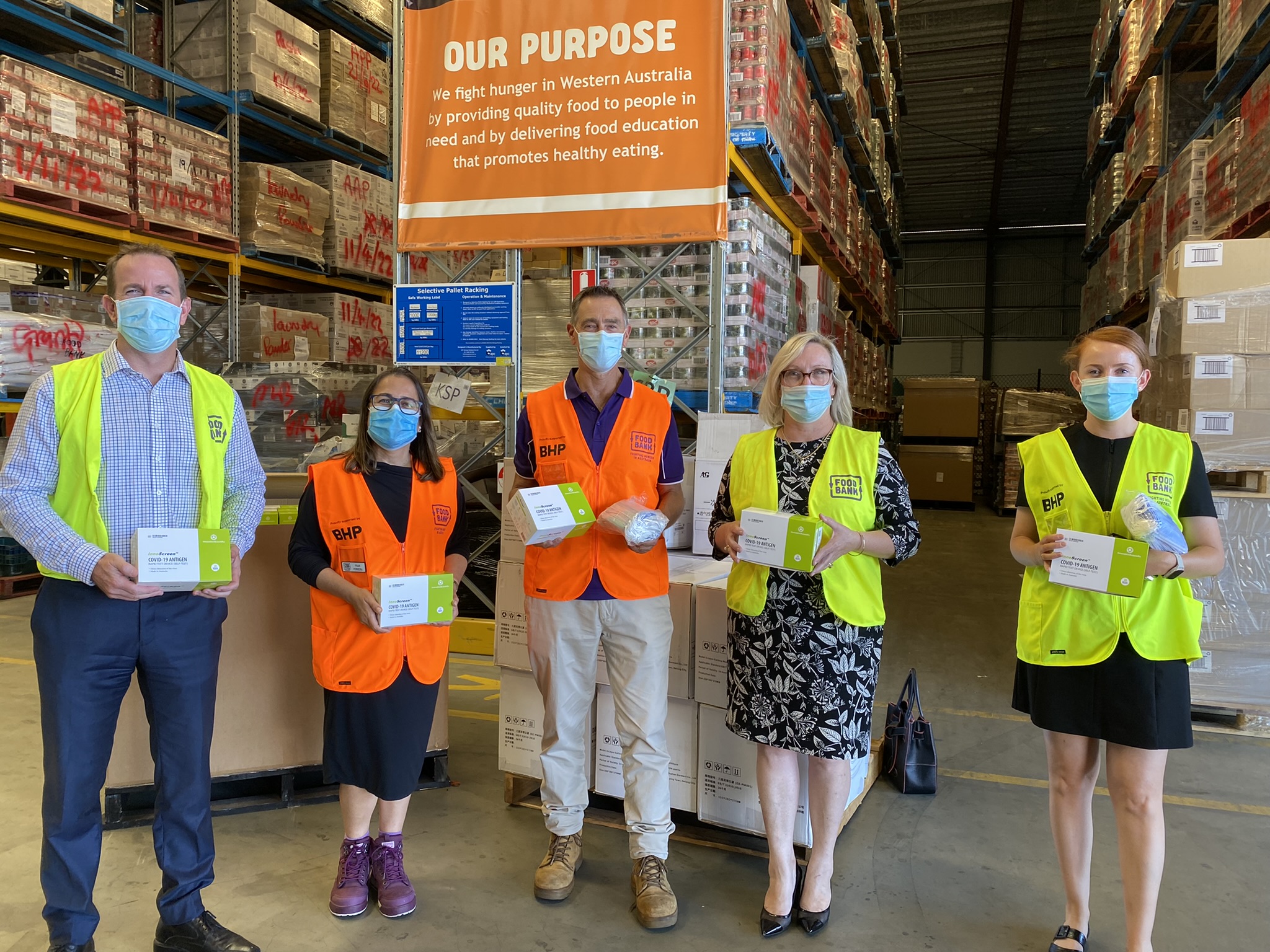 Troy Dennis, Fran Ferreira, Steve Martin, Catherine Stoddart and Lucy Granger at the Foodbank WA warehouse with some of the RAT kits and masks that will be distributed