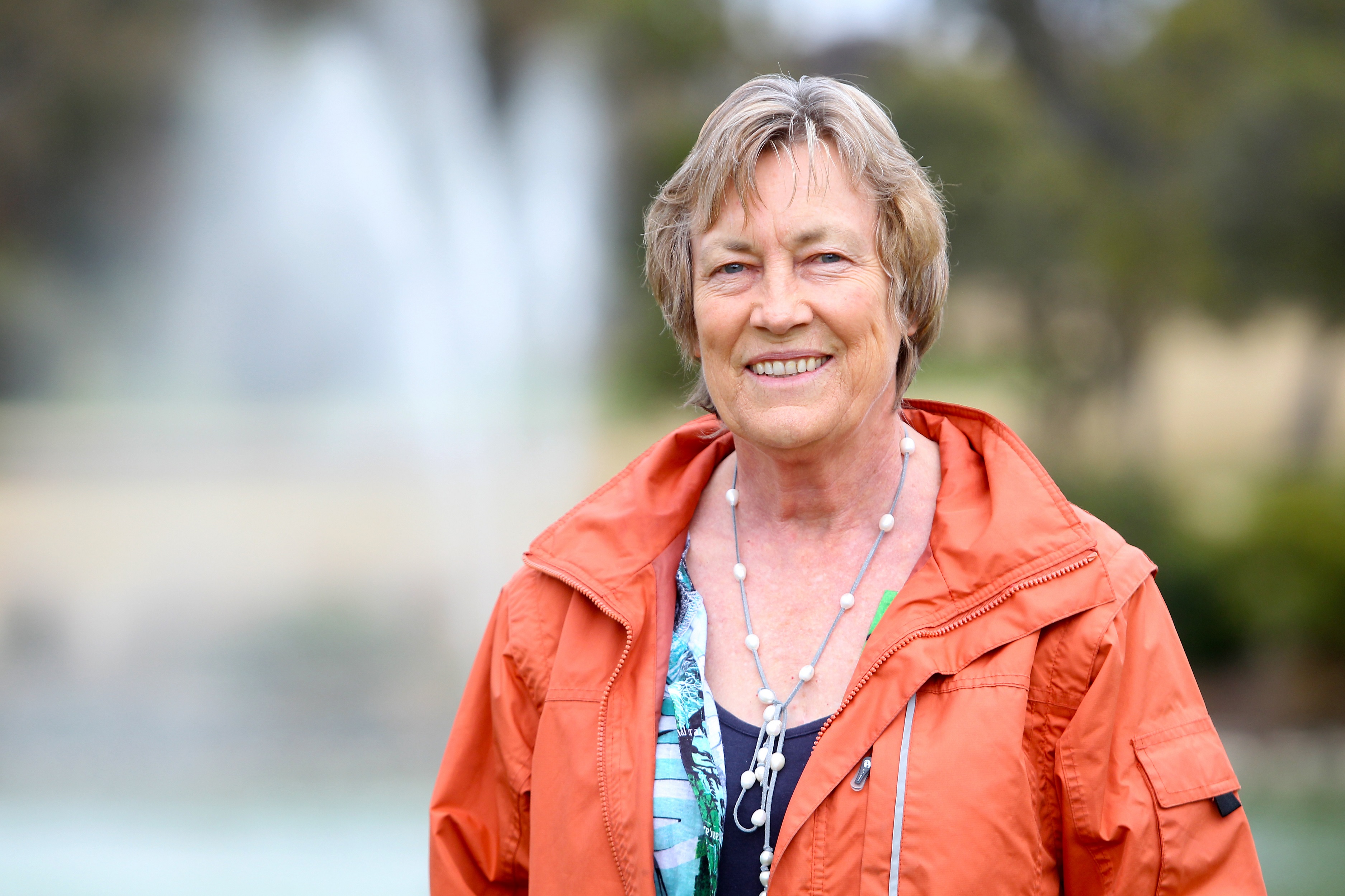 Dr Christine Jones smiling in front of a man-made lake, blurred out. 