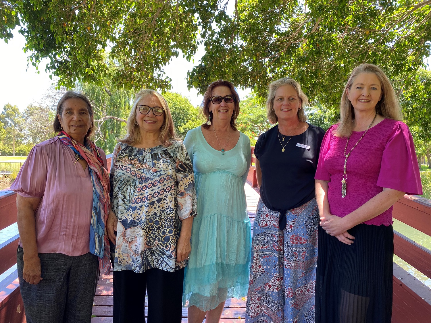 Image of five women outdoors under a tree looking at the camera