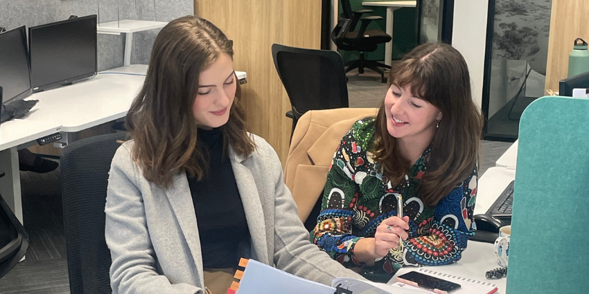 Two people sitting at a desk reading through documents. 