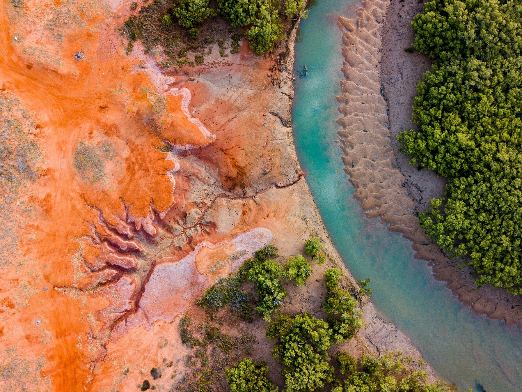 Image of creek with red dirt and mangroves