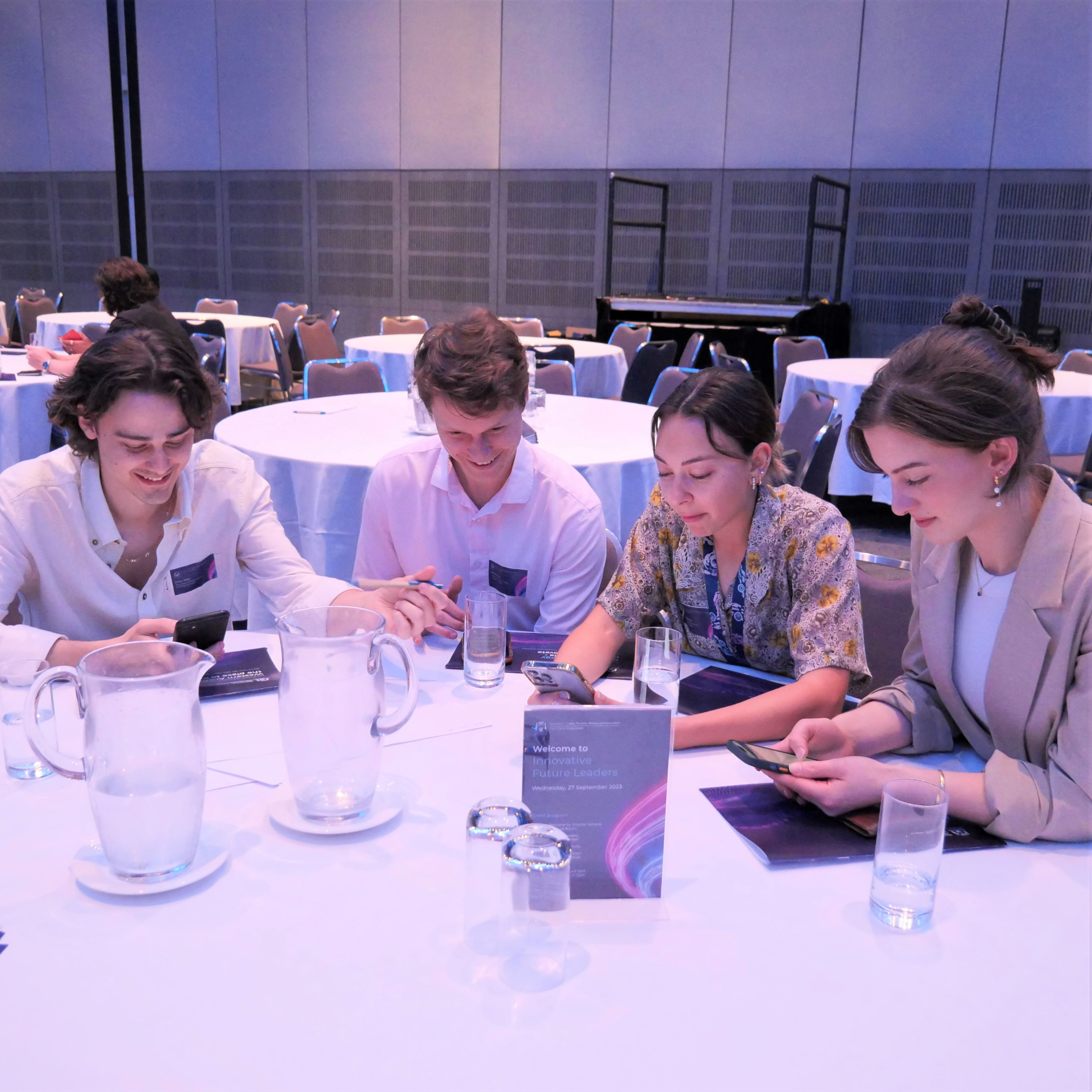 4 graduates are working together at a table.