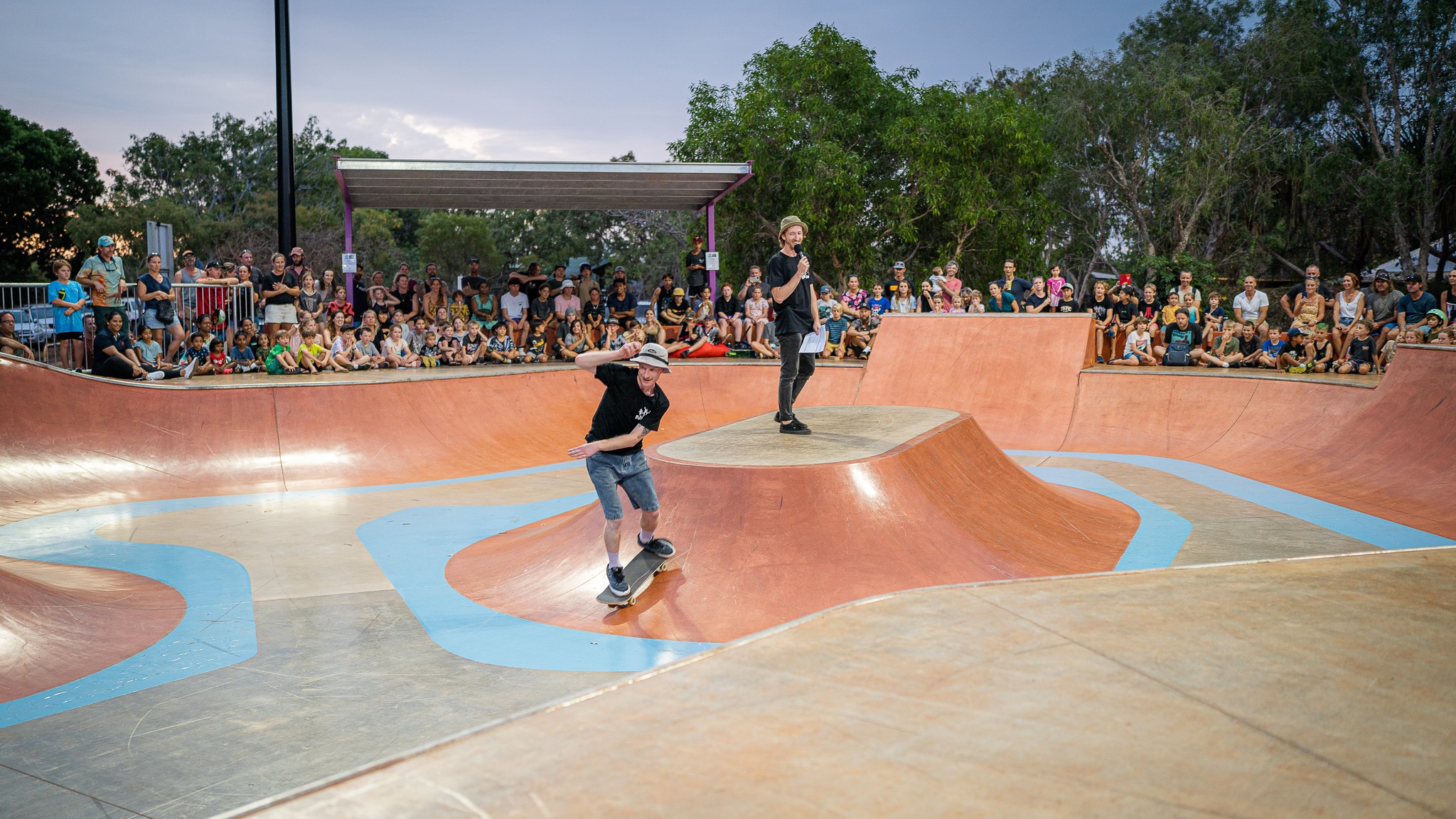 Photo of someone skating in a skate competition in front a big crowd of young people 