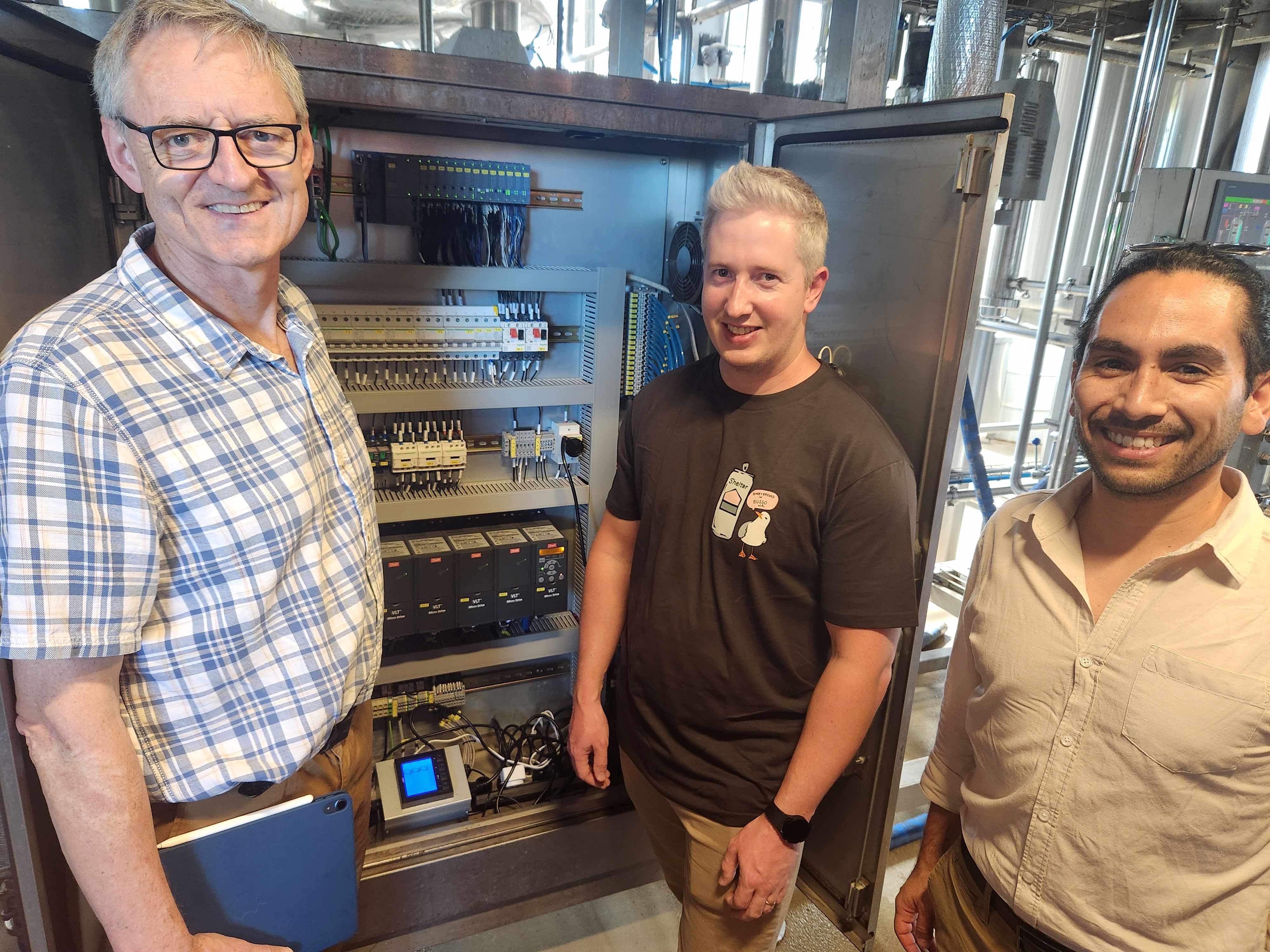 Three men standing next to a big computer.