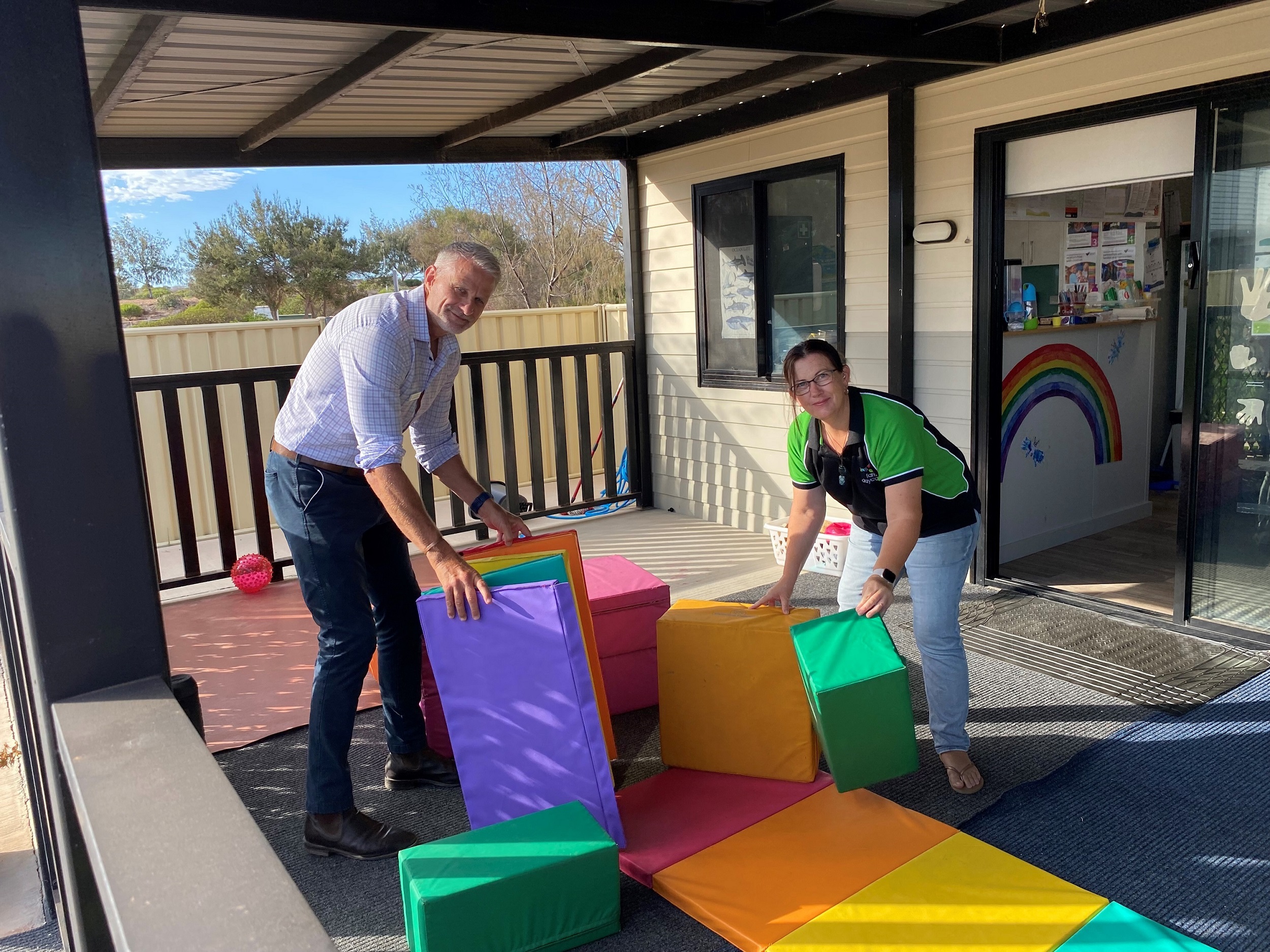 Photo of two adults rearranging a play area of an early education care centre