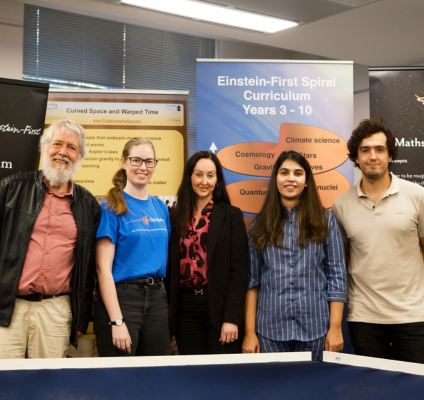 A diverse group of individuals stands together in front of a large banner, smiling