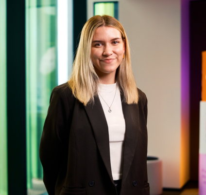  A professional woman in a suit poses confidently in front of a vibrant, colorful wall