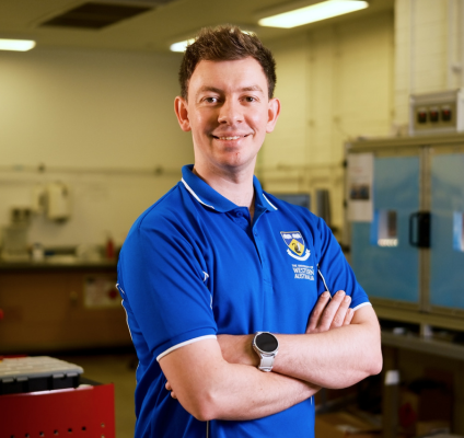  A man wearing a blue shirt stands in a laboratory, surrounded by scientific equipment and research materials.