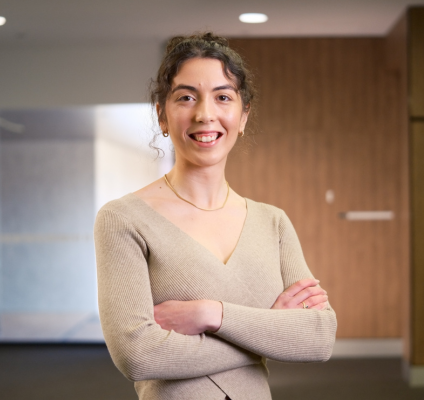 A woman in a tan sweater stands in an office