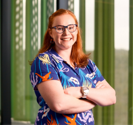  A woman with glasses and a floral shirt poses in front of a window