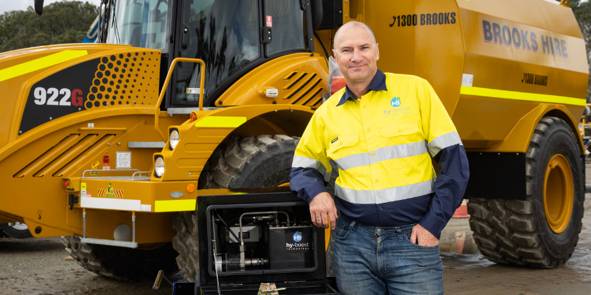 man in yellow standing in front of orange truck