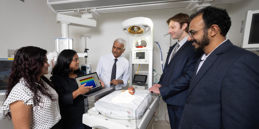 group of medical professionals standing around a medical bed discussing