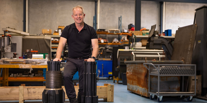 man in a workshop leaning against large metal parts