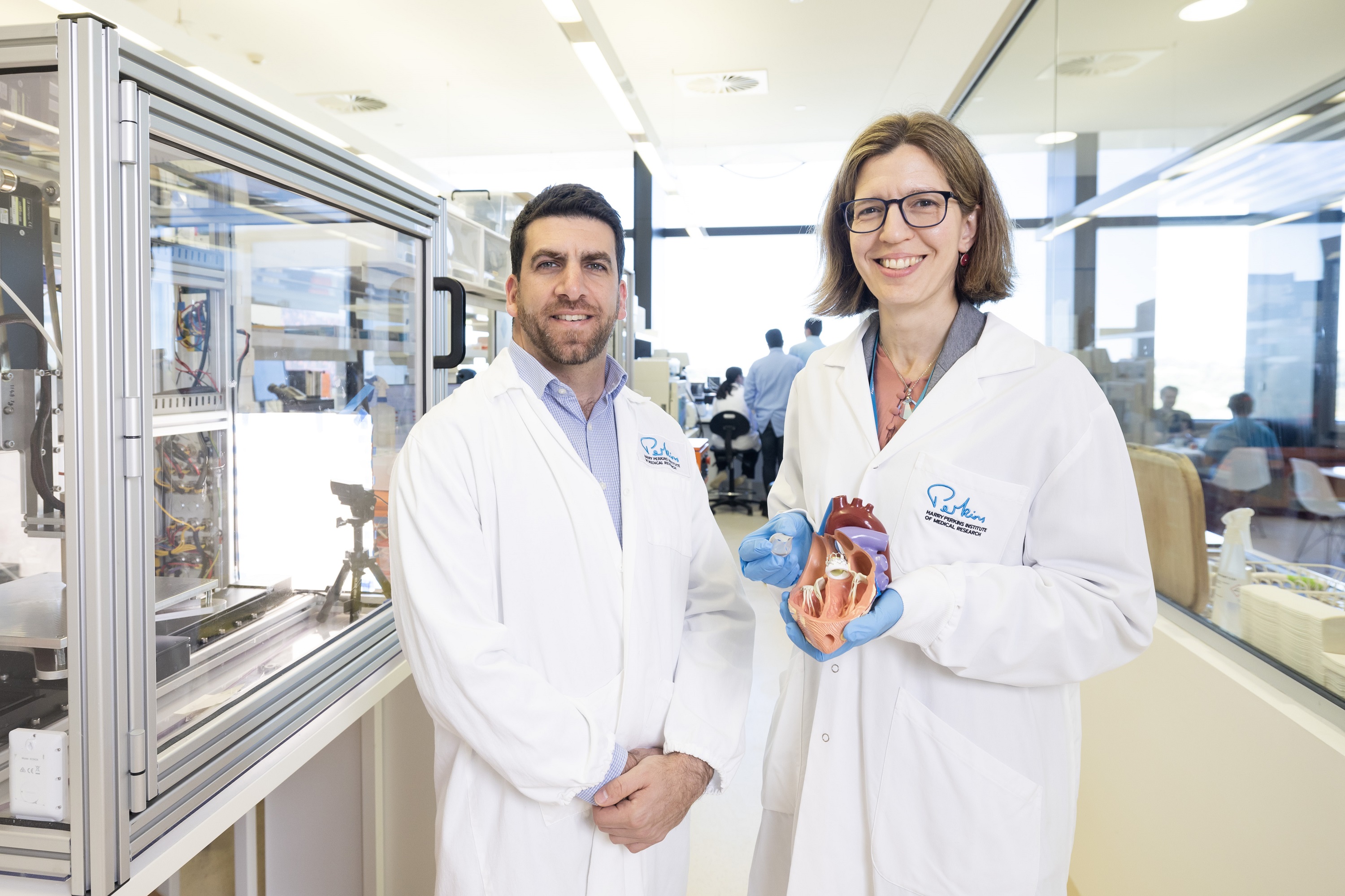 one male and one female scientists standing in laboratory holding a synthetic heart