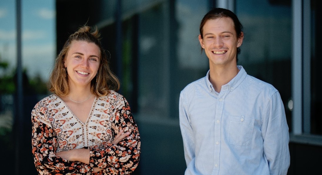 Two smiling young employees standing in front of an office