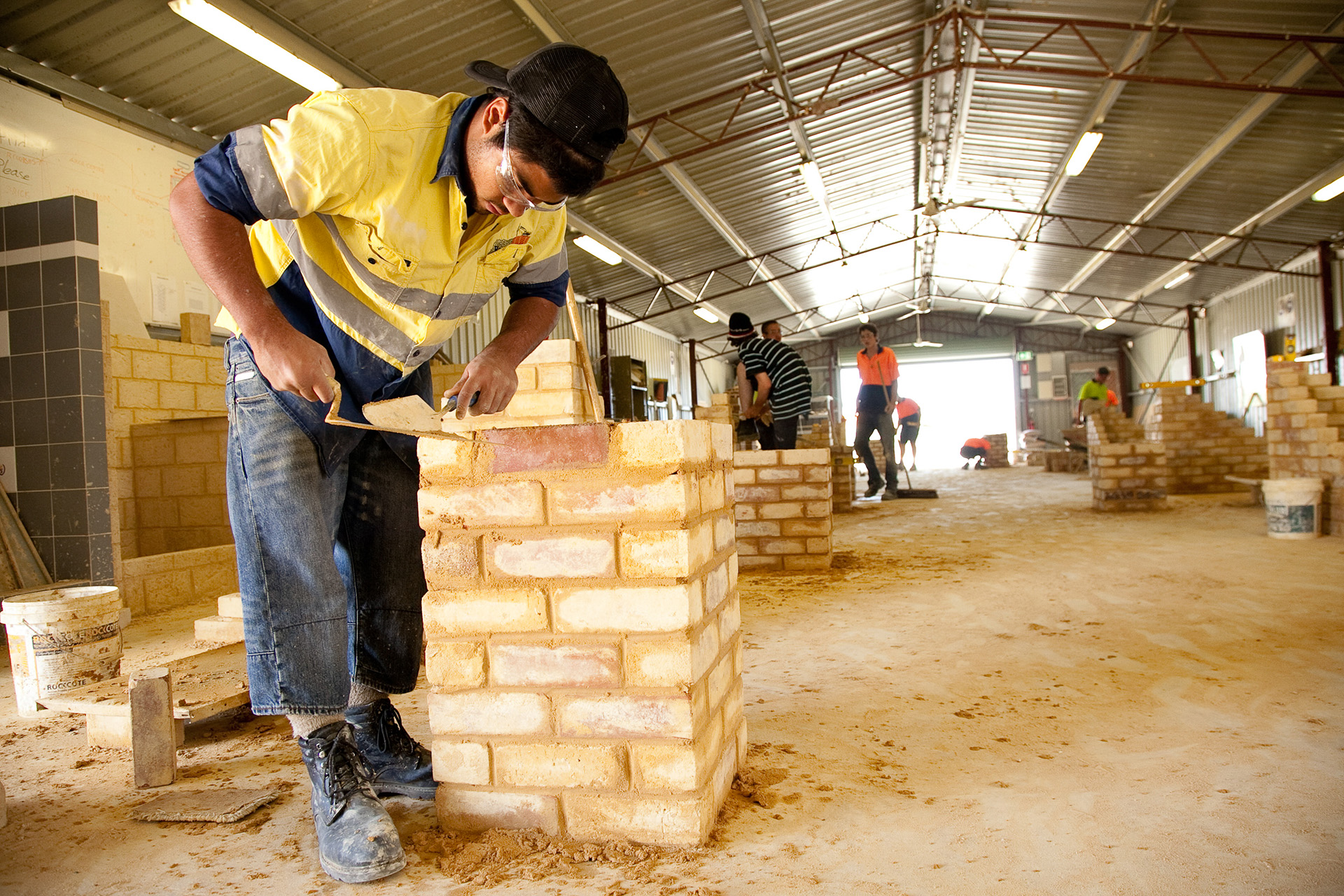 A bricklaying training session, where individuals are practicing their skills in a structured workshop environment.