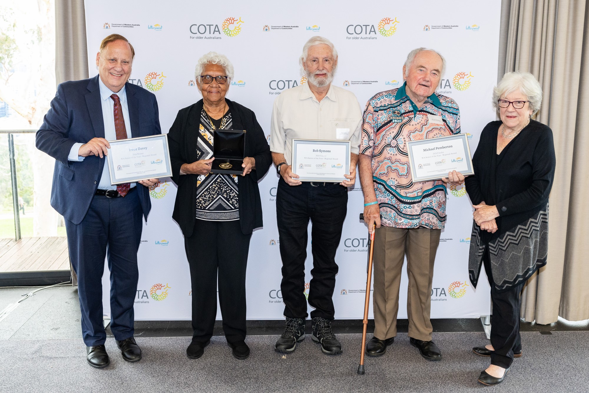 Photo of a group of five people formally dressed and holding certificates and a medal