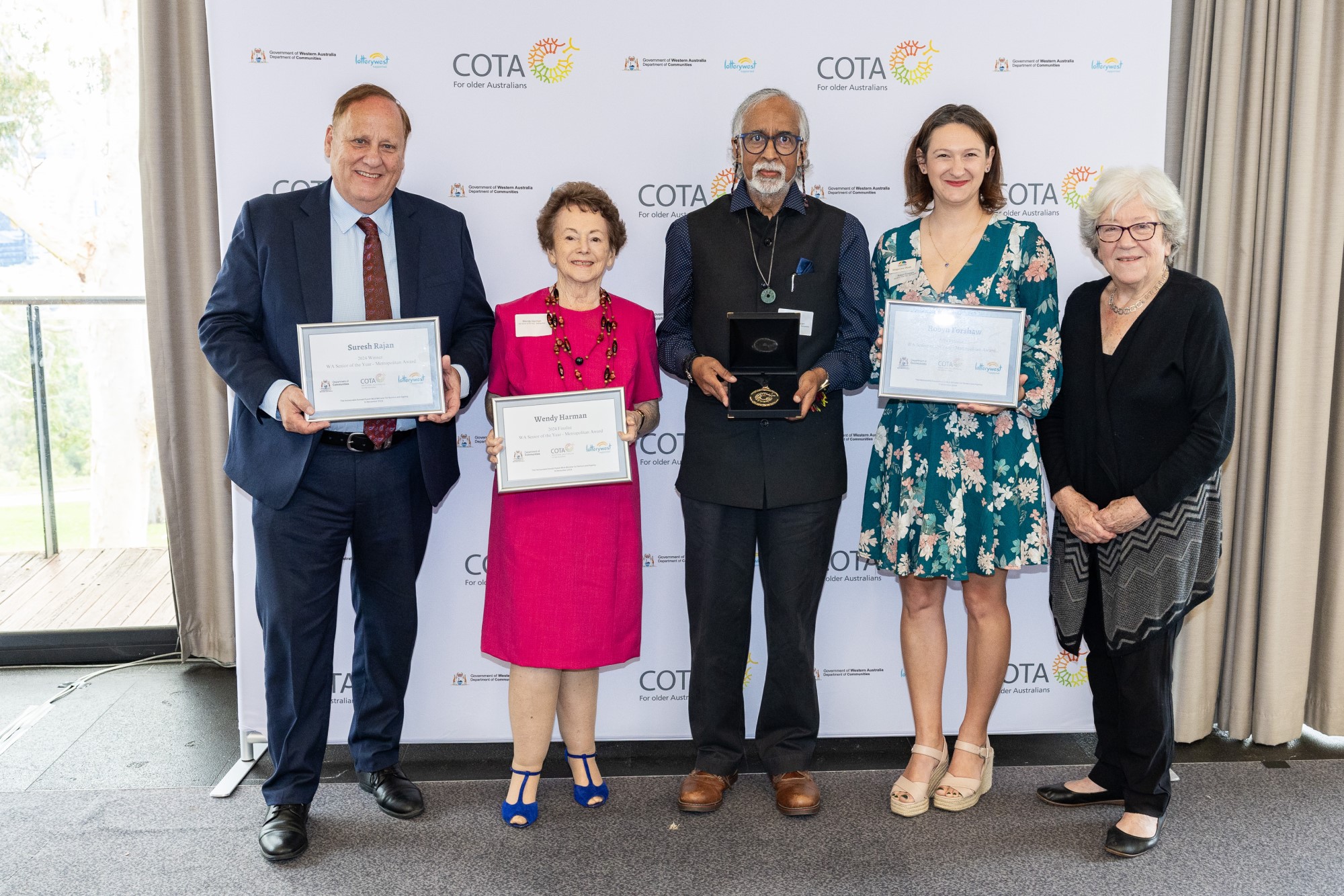 Photo of a group of five people formally dressed and holding certificates and a medal