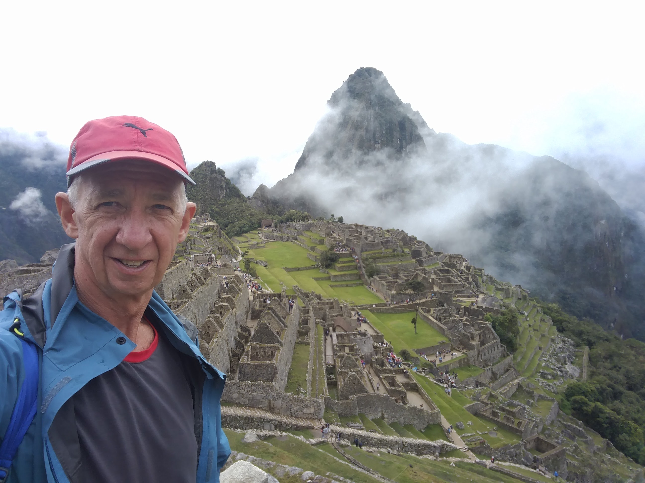 A photo of an older man with Machu Picchu in Peru in the background