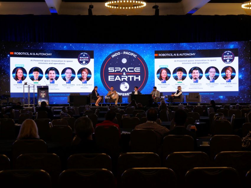 Taken from the back of the conference room, guest speakers engage in a panel dicussion