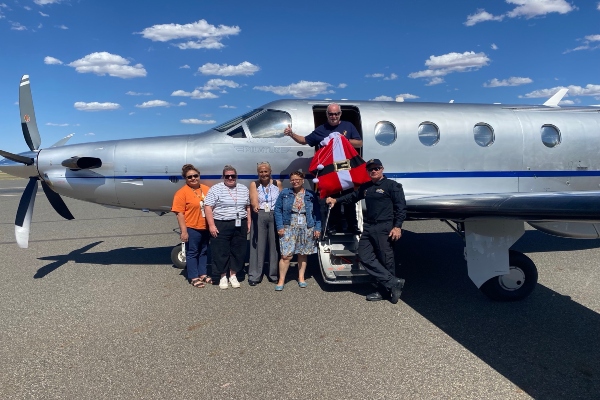 Image of Communities staff standing outside a light aircraft with a santa bag 