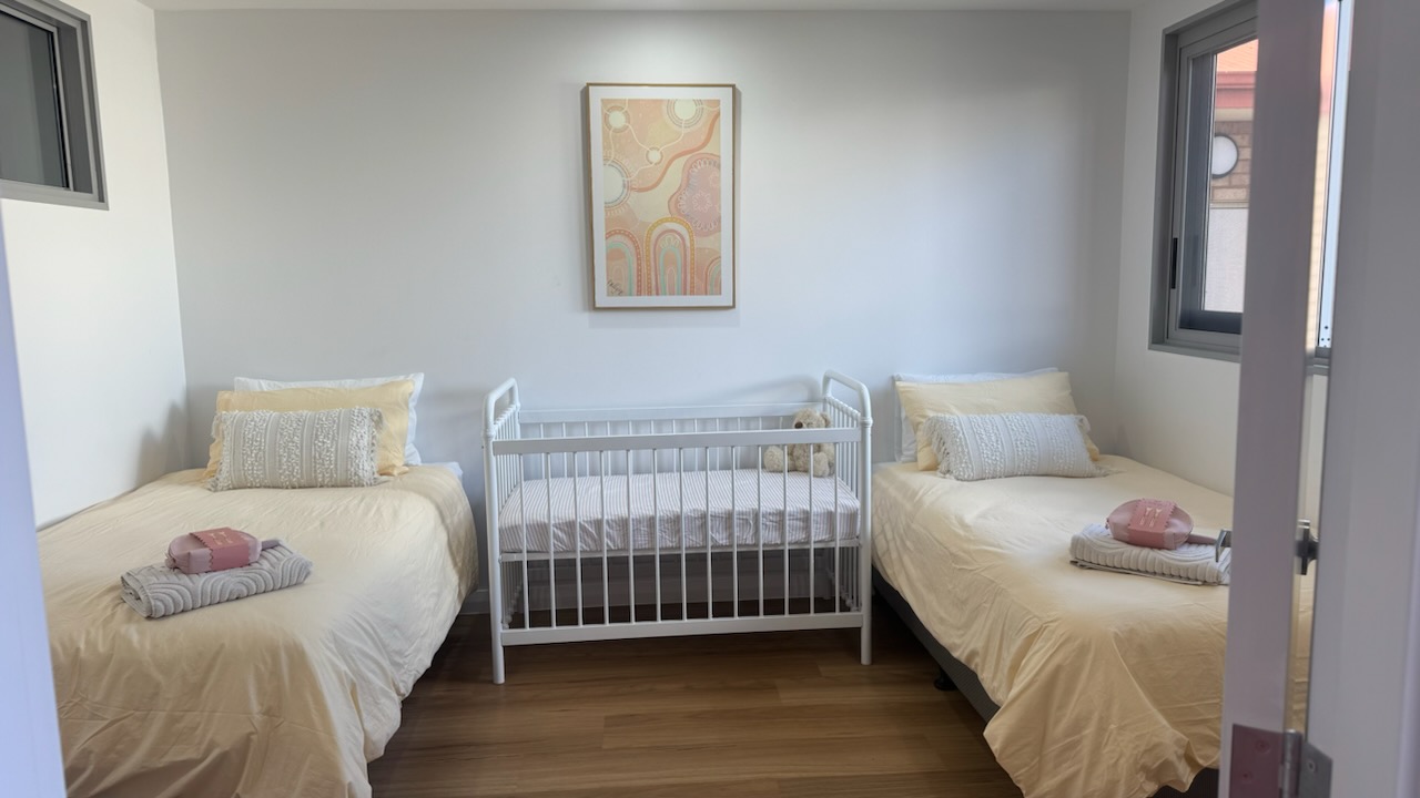 Image of one of the rooms in the Goldfields Women's Refuge  including two single beds and a cot