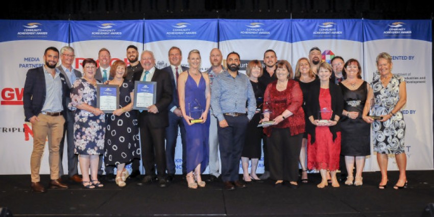 People standing on stage with awards