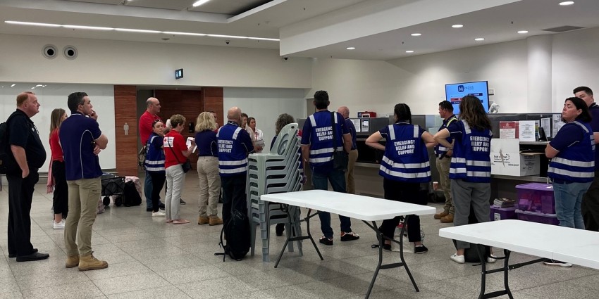 Image of dept of communities and red cross staff in an airport briefing