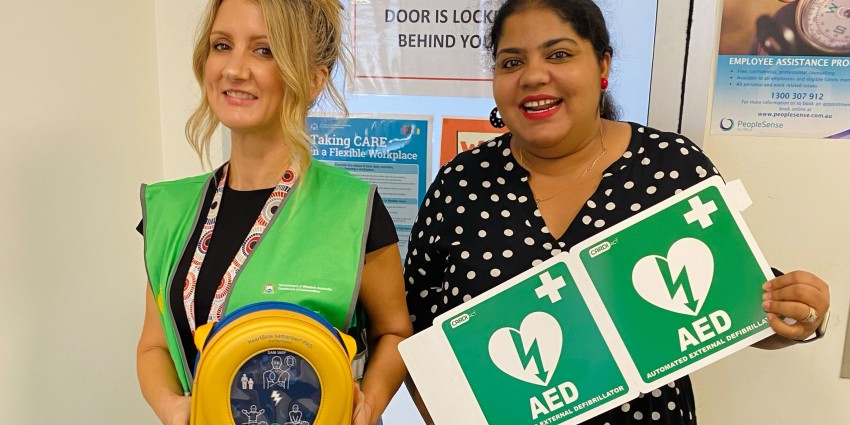 Photo of two female Communities staff members with a defibrillator machine