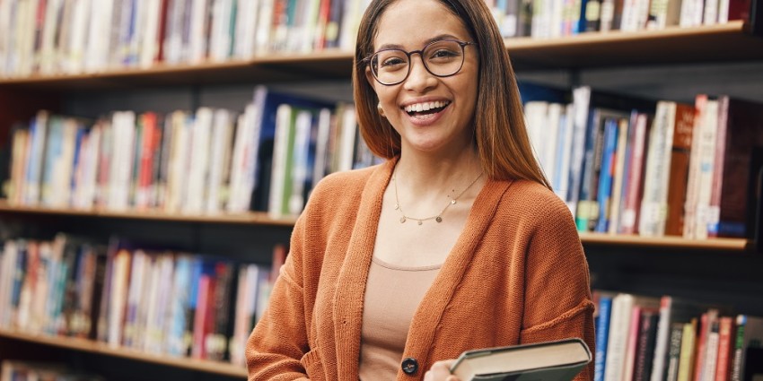 Smiling university student holding a book. 