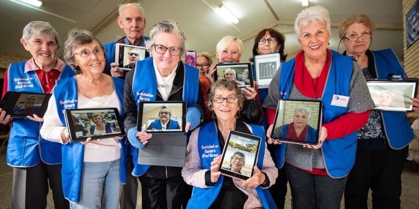 Photo of a group of happy seniors volunteers holding ipads
