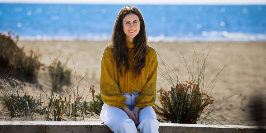 A picture of a young lady sitting in front of a seascape