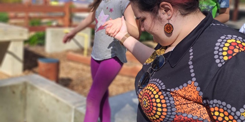 A picture of a lady holding a child's hand as they walk across a balance beam