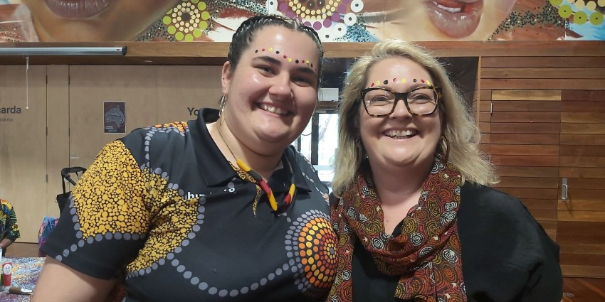 A picture of two ladies with black, red and yellow face paint smiling