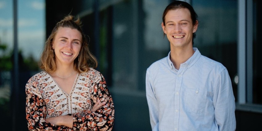 Two smiling young employees standing in front of an office