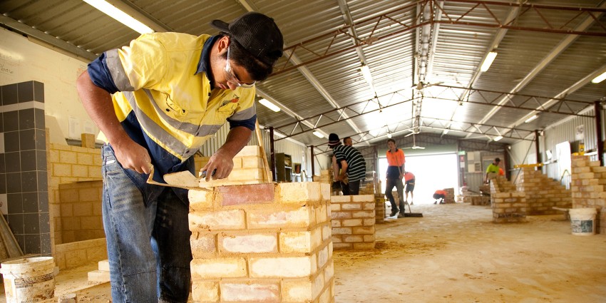 A bricklaying training session, where individuals are practicing their skills in a structured workshop environment.