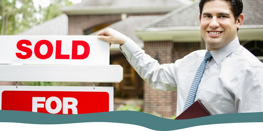 Real estate agent pointing to a sold sign on a property