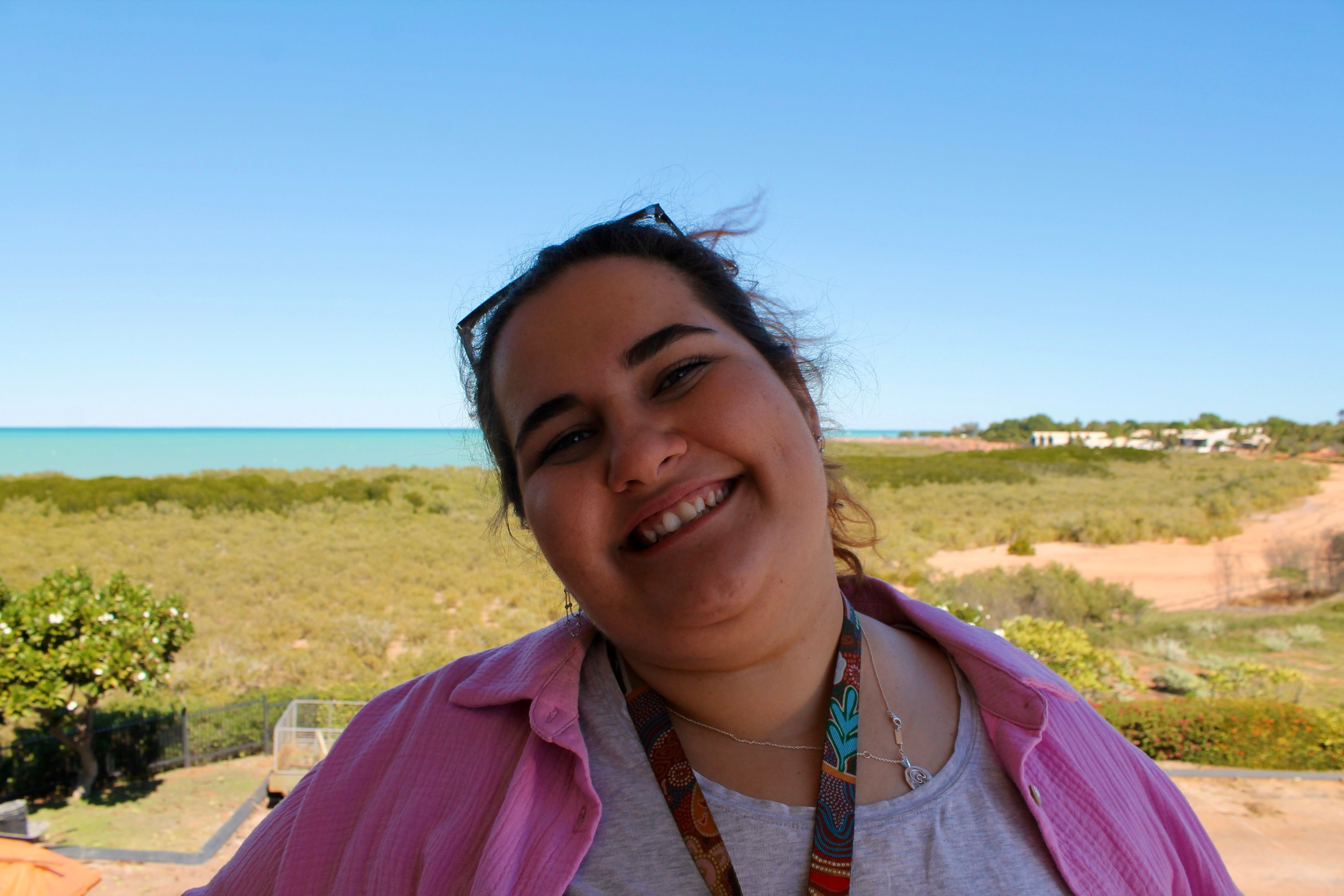 A picture of Emmerson smiling in front of a sunny seascape