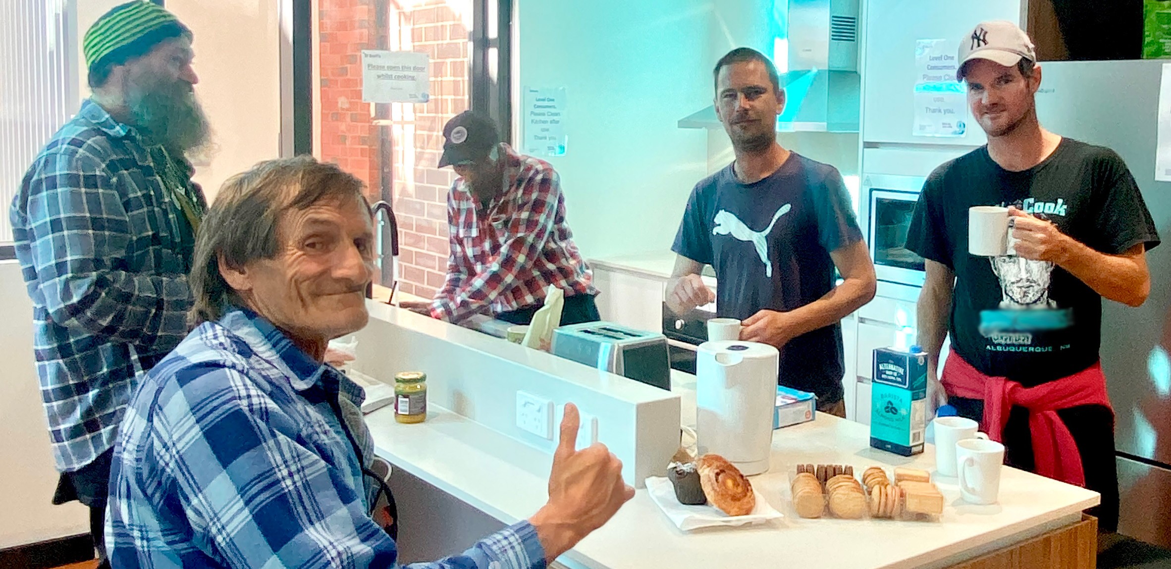 A group photo of 5 men enjoying morning tea in the Saint Barts kitchen.